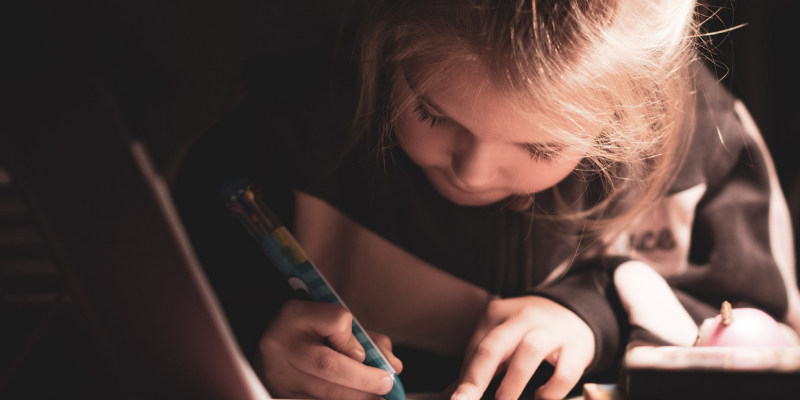 Image of a child with a crayon in her hand drawing something